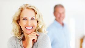 Joyful mature woman smiling while blur man in background